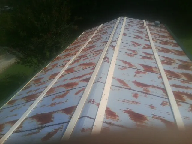 Rusted metal roof panels with new wood purlins before replacement — Storm Damage Roof Repair in Willow Spring by Roofing Brothers