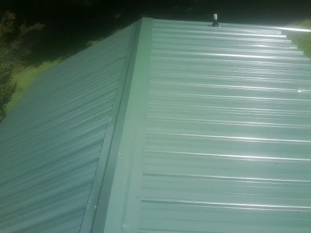 New green metal panels meeting at the ridge of a roof — Flat Roof Repair work by our crew in Willow Spring
