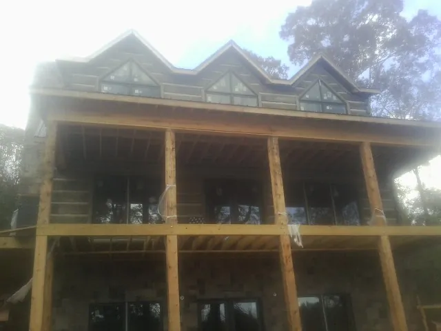 Dormers and porch framing on a large log home under construction — Roof Coating work by our crew in Willow Spring