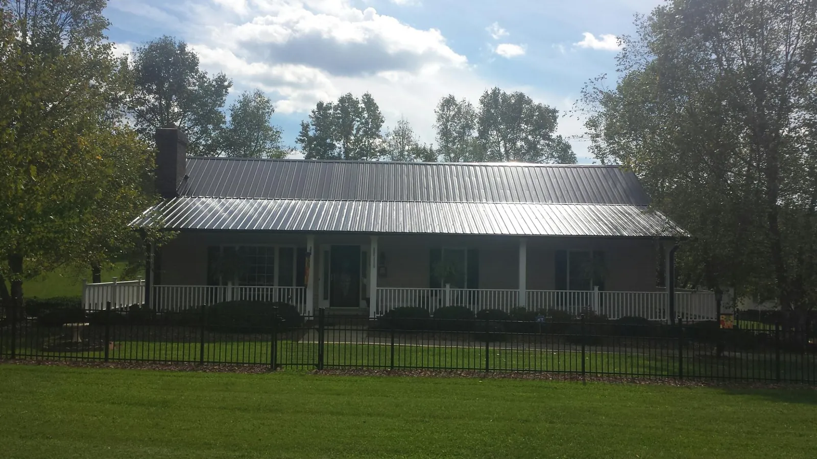 Gray metal roof on a brick ranch with a full width front porch — Gutter Guard Installation work by our crew in Willow Spring