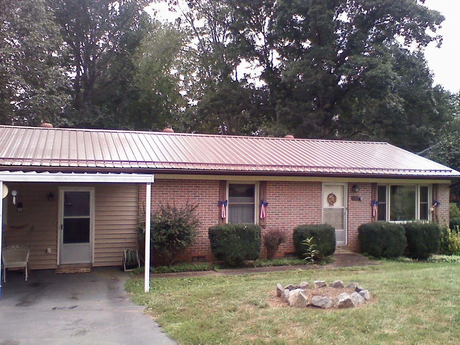 Bronze metal roof and carport on a brick ranch home — Roof Repair work by our crew in Willow Spring