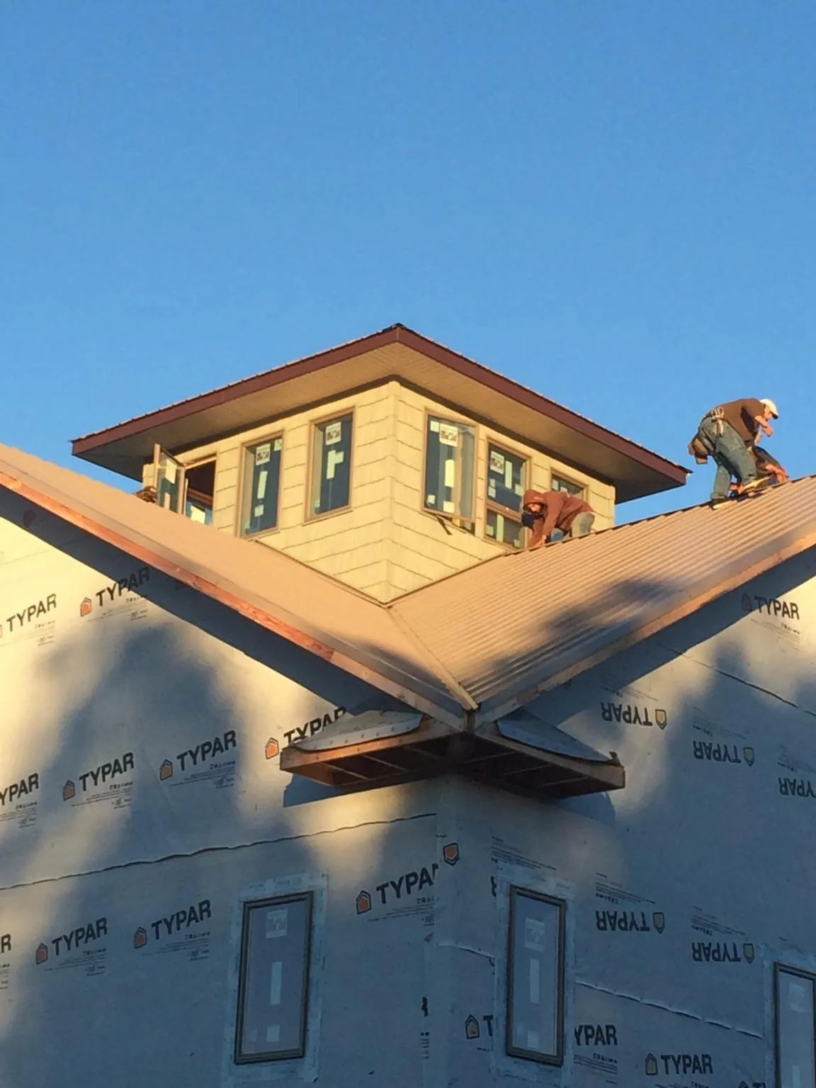 Roofers working around a rooftop cupola on a new metal roof at sunset — Roof Waterproofing in Willow Spring by Roofing Brothers